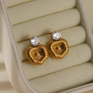 Macro shot of gold heart earrings with zircon inlay and sunburst pleated metal texture