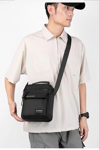 Front view of men's black nylon crossbody bag worn by model for business commute