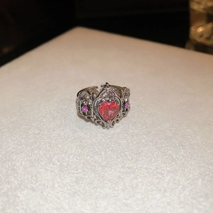 Macro shot of silver ring featuring heart-shaped red gemstone and hollow floral carving
