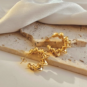 Detailed view of 18k gold plated twisted hoop earrings on elegant stone surface