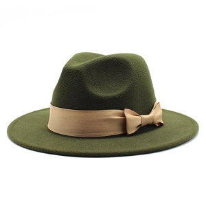 Close-up view of a dark green felt fedora hat featuring a stylish beige bow ribbon band.