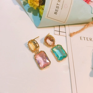Boucles d'oreilles baroques dorées avec cristaux colorés présentées sous un angle élégant