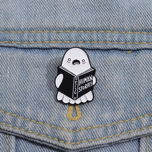 Detail of cute ghost enamel pin reading Human Stories on a blue denim jacket pocket