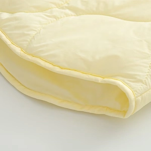 Close-up of light yellow quilted cotton jacket showing fabric texture and stitching