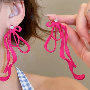 Detail of rose pink ribbon drop earrings with matte finish and sparkling rhinestones