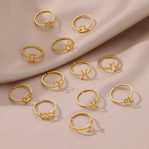 Detailed set of 12 gold minimalist zodiac symbol rings on elegant beige satin fabric