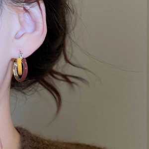 Macro shot of tricolor enamel hoop earrings in silver, yellow, and deep red finishes