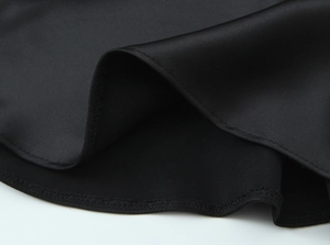 Close-up of black satin shirt hem showing high-quality stitching and smooth fabric texture