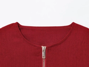 Detail shot of a burgundy linen jacket featuring a round neck and front metal zipper