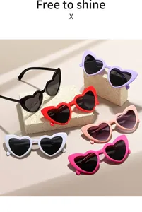 Close-up of heart-shaped sunglasses in multiple colors displayed on a textured stone base
