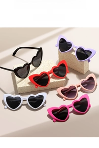 Close-up of heart-shaped sunglasses in multiple colors displayed on a textured stone base