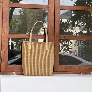 Detail of vintage striped cotton tote bag leaning against a wooden window frame