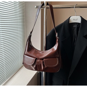 Close-up of deep brown leather shoulder bag featuring two magnetic front pockets