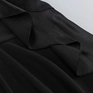 Detail of ruffled hem with satin sheen and delicate overlock edge on black dress