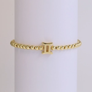 Detailed view of 18k gold plated beaded bracelet with Gemini zodiac sign pendant