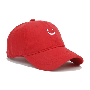 Close-up of red cotton baseball cap with white smile embroidery and detailed stitching