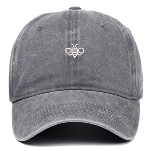 Close-up of fine white bee embroidery on a grey washed cotton baseball cap with curved brim