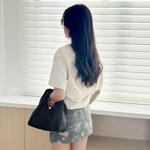 Minimalist black PU cloud tote bag held by a model in casual streetwear outfit