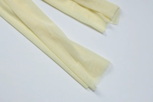 Detail view of light yellow sheer mesh fabric texture with fine breathable netting