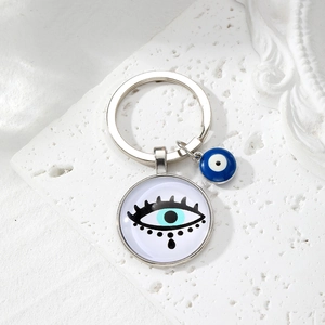 Detail of silver Evil Eye keychain with blue glass beads on elegant stone surface