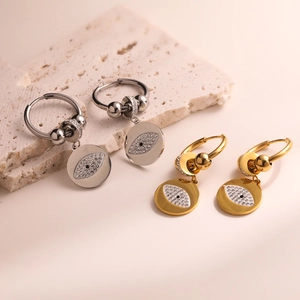 Gold and silver evil eye hoop earrings with cubic zirconia on a minimalist stone base
