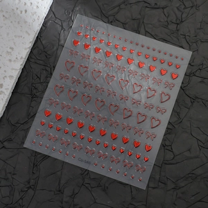 Macro detail of 3D embossed red bow and heart nail stickers with metallic gold accents