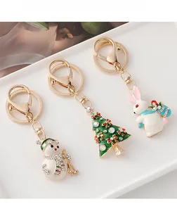 Detail of Christmas tree and snowman enamel keychains with rhinestones on ceramic tray