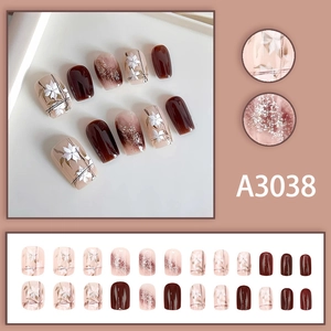 Caramel and nude press-on nails with white flower accents and silver glitter finish