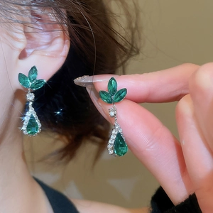 Detail of elegant silver earrings with marquise-cut green gemstones and crystal accents
