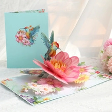 Macro detail of 3D popup hummingbird card showing intricate laser-cut floral craftsmanship