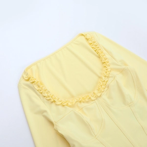 Detail view of the yellow long sleeve top showing lettuce trim collar and structural stitching