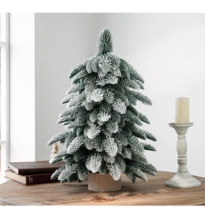 Close-up of artificial mini Christmas tree with snow-flocked PE needles on a wooden base
