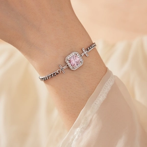 Detailed shot of pink zircon cross bracelet with silver chain on model's wrist