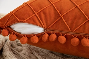 Detail of hidden zipper on caramel velvet diamond quilted pillow with pompom trim