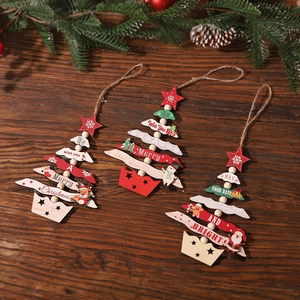 Three painted wooden Christmas tree ornaments with twine hangers on dark wood