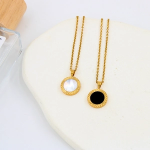 Detail of minimalist gold necklaces with natural shell and black stone circular pendants
