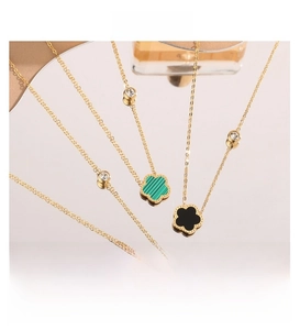 Detail of clover necklaces in gold finish with green and black stone inlays and zircons