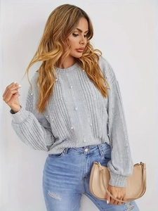 Détail du pull en maille gris clair avec perles décoratives et texture côtelée