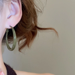 Close-up of moss green resin hoop earrings worn by a model in a minimalist style