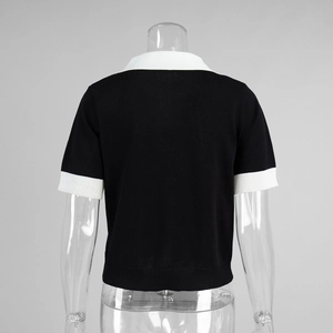 Détail des poignets en maille côtelée blanche contrastée sur un polo noir ajusté