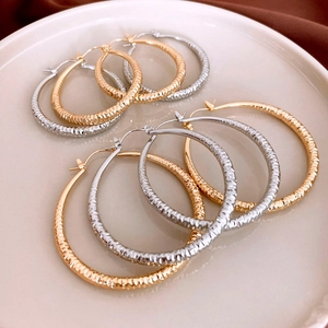 Detailed view of textured gold and silver hoop earrings displayed on a ceramic tray
