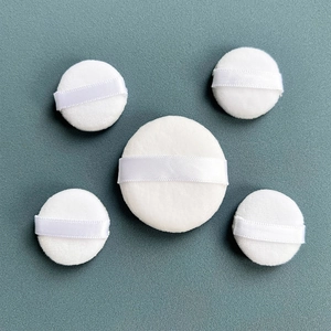 Detailed macro view of five round white crystal velvet powder puffs with ribbon handles