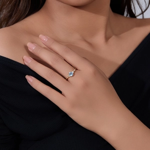 Close-up of gold ring with blue topaz and white side stones worn by a model gracefully