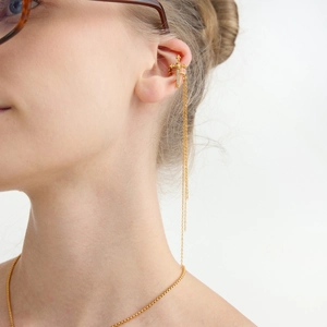 Detail of a gold dagger ear cuff with micro-inlaid zircons and fine tassel chain on model