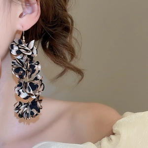 Detailed close-up of fashion fabric flower tassel earrings worn by a model