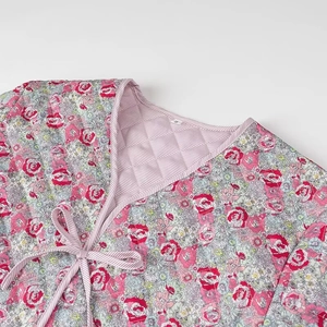 Detailed view of V-neck tie closure on quilted floral jacket with striped lining