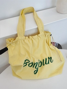 Yellow canvas tote bag with green Bonjour lettering and drawstring closure in minimalist style