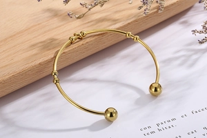 Bracelet jonc doré élégant en forme de cœur avec fleurs séchées sur une surface en bois