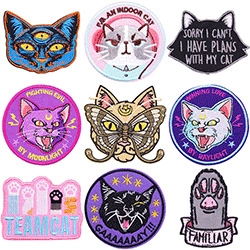 Detail view showing nine colorful embroidered cat-themed iron-on patches for clothes