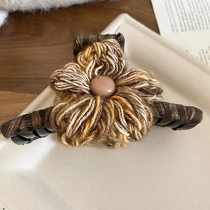 Detailed macro view of handcrafted knit flower hair claw with vintage checkered fabric wrap